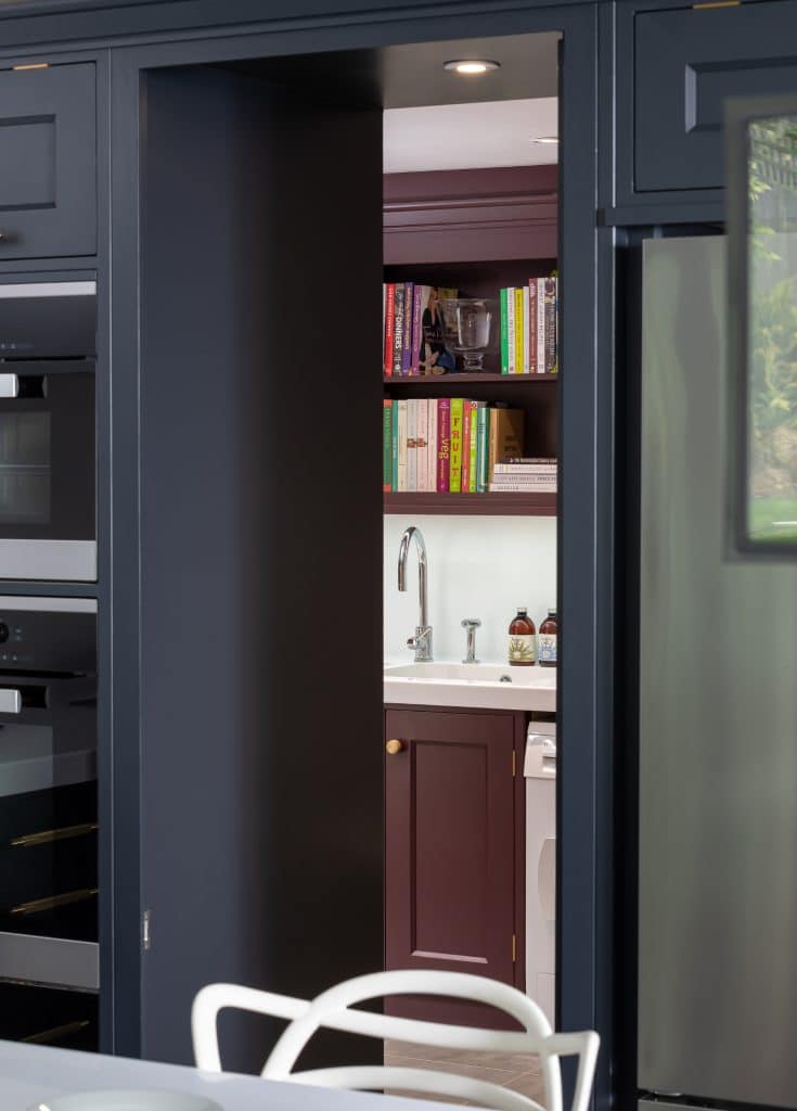 Hidden door with handpainted grey cabinetry and damson bootility room.