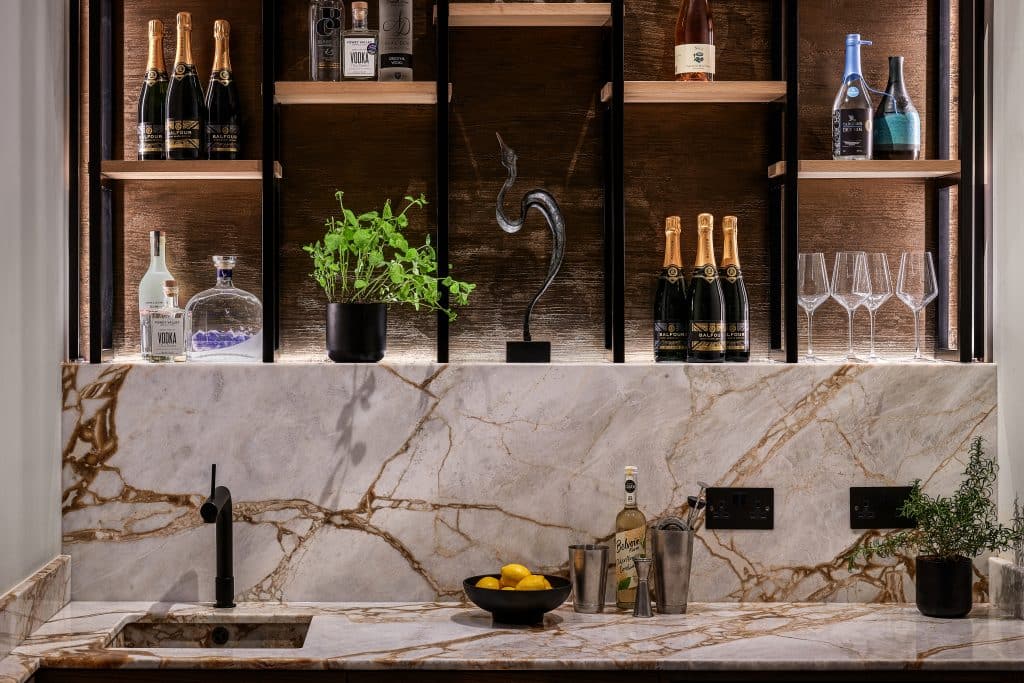 Penthouse home bar with black shelving, marble splashback and metallic worktop.