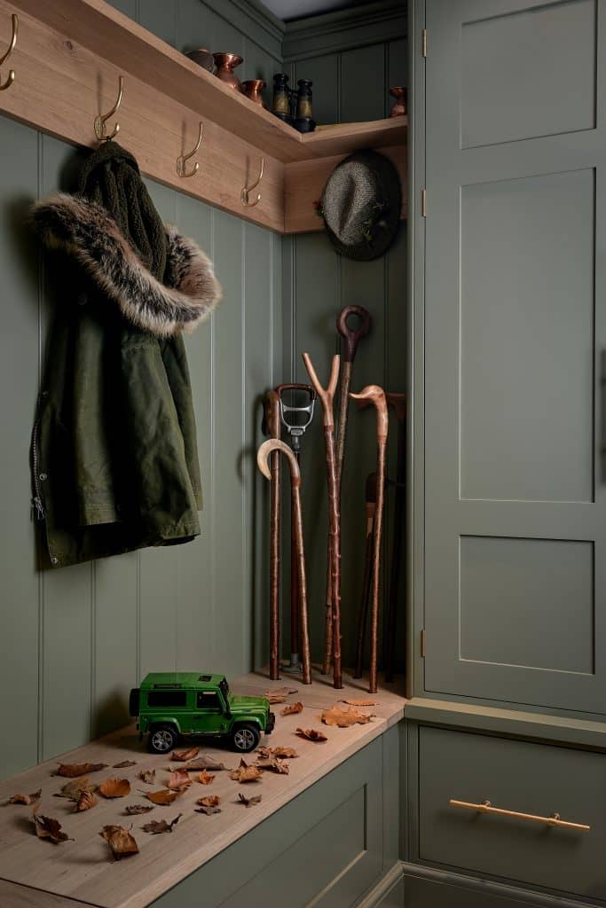 Handmade walking sticks with oak bench and oak shelving with green painted cabinetry.