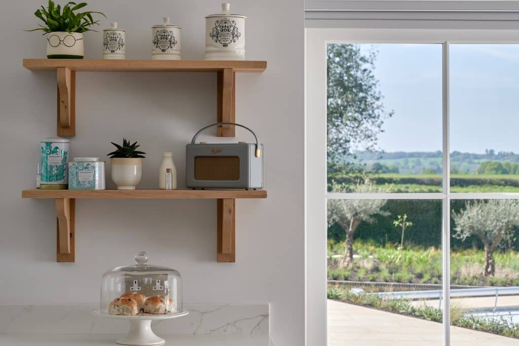Open oak shelving with cake dome and views of countryside