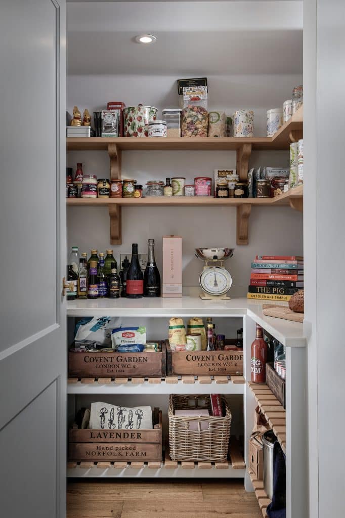 Walk-in pantry with dry groceries, oak shelving and wicker storage baskets.