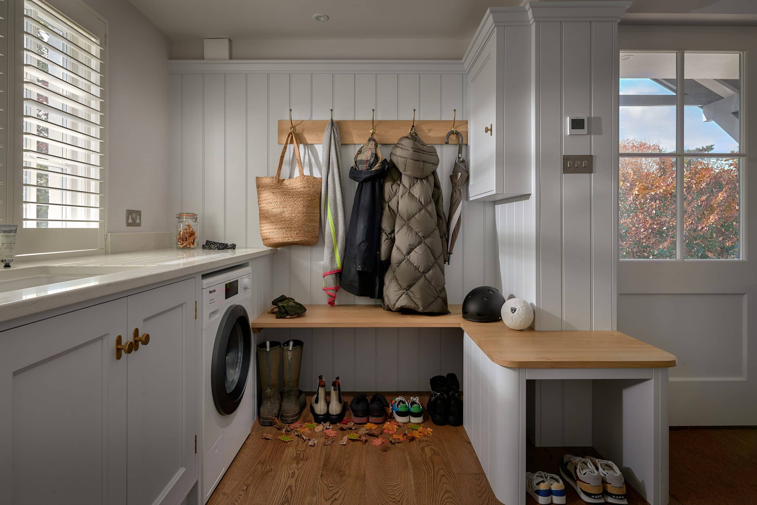 Boot room with coats on pegs, boots and sporting equipment