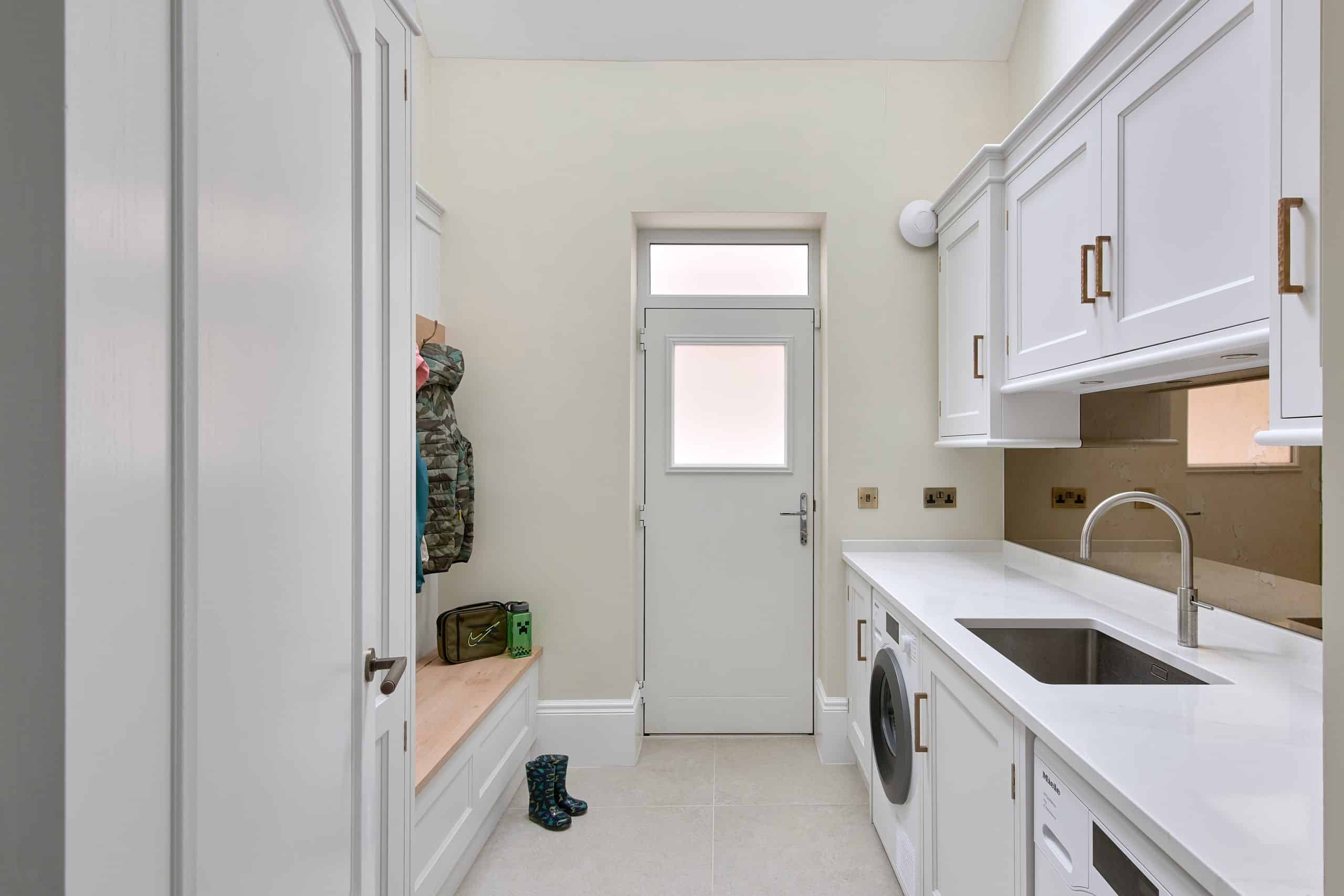 Luxury bespoke boot room with utility laundry area and pegs with bench seating.